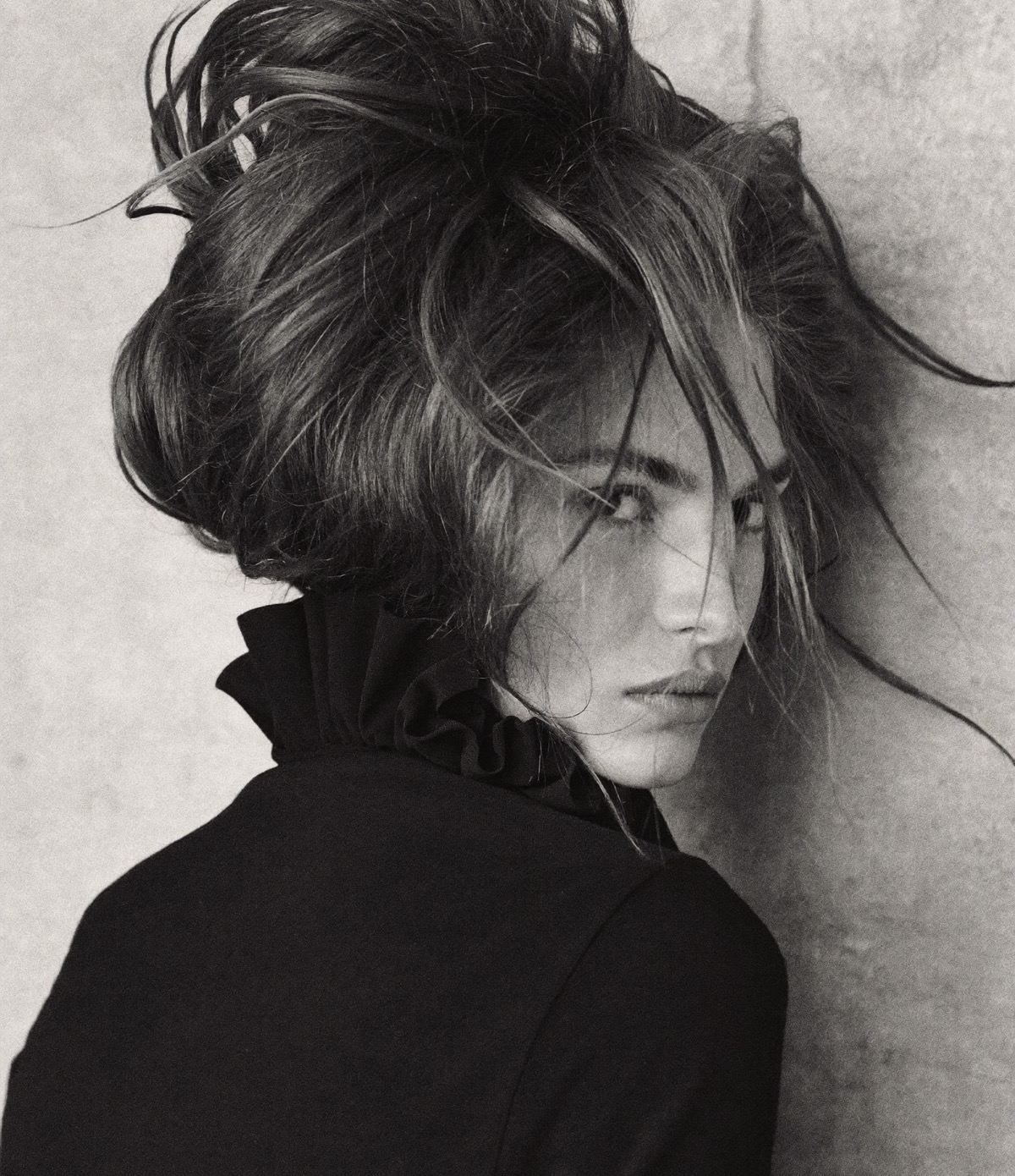 Black and white portrait of a woman with tousled waves falling across her face