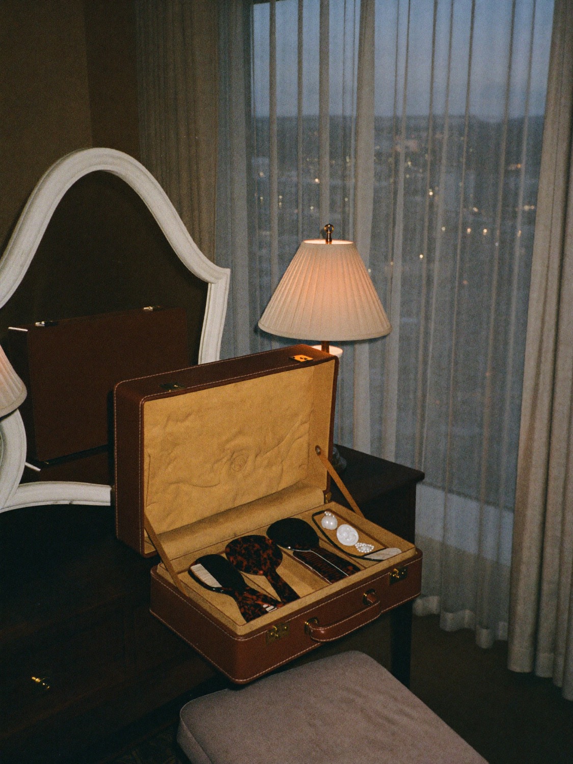 A hotel suite vanity at dusk with an open leather stylist's case